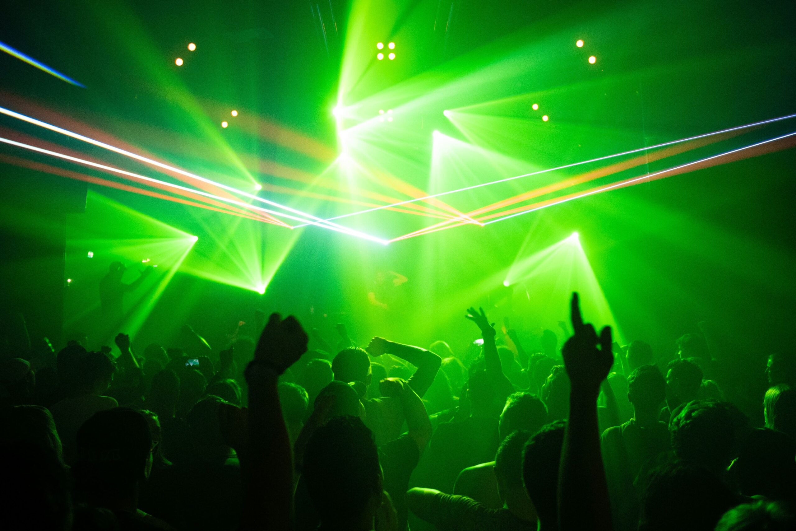 Green laser beams crossing a crowded concert venue