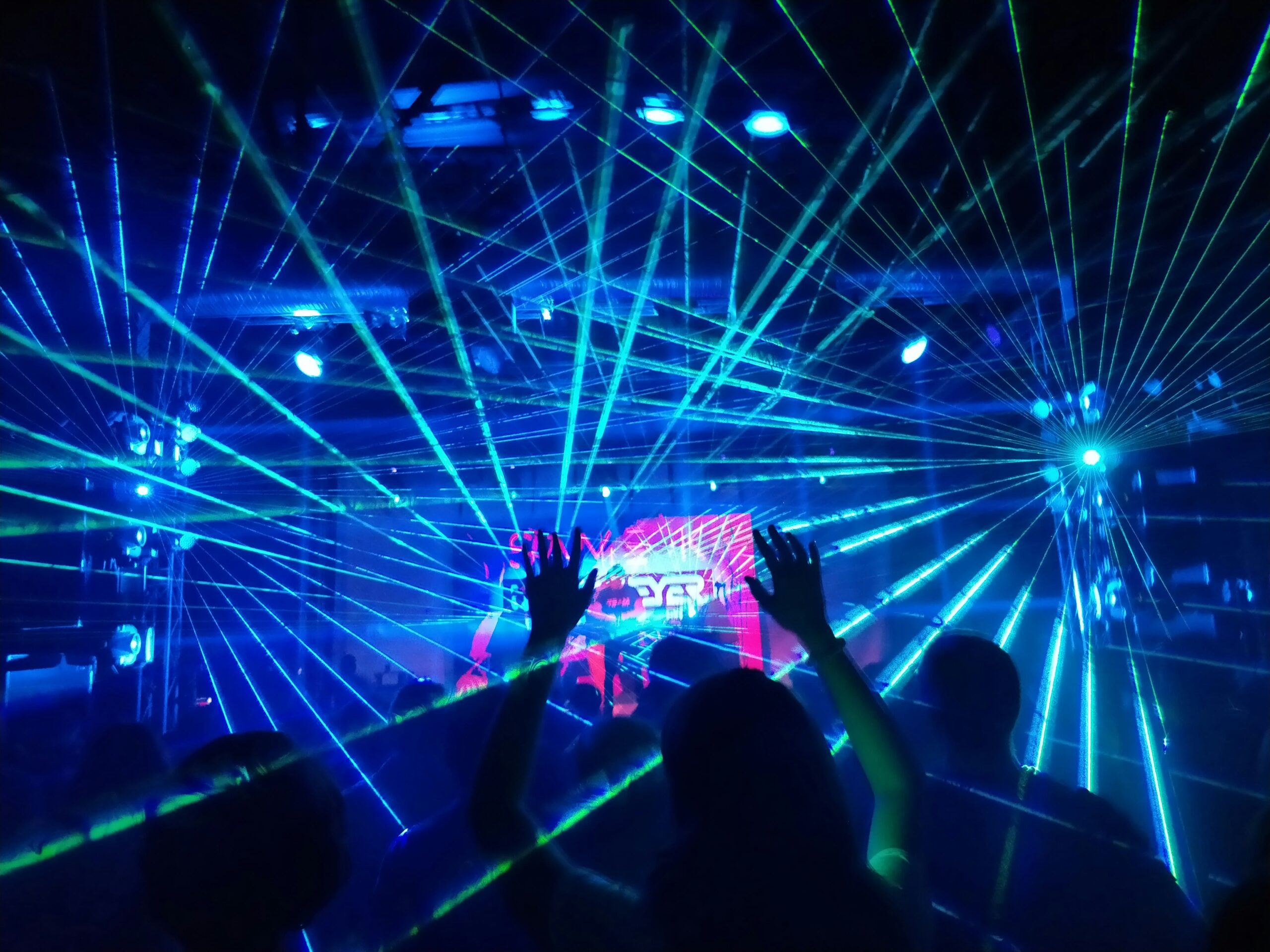 Blue and green laser beams crossing a crowded concert venue